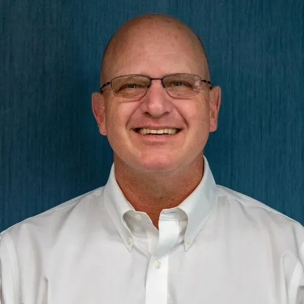 A man with glasses and bald head wearing a white shirt.